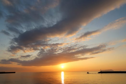 Sunset sky with clouds over the sea. Bright orange sun over the ocean.