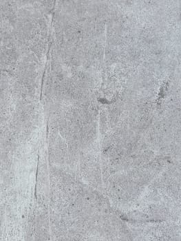 A grey and white wall with a few spots of color. The wall is made of concrete and has a rough texture