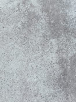A grey and white wall with a few spots of color. The wall is made of concrete and has a rough texture