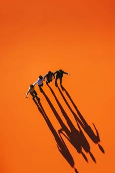A group of people are playing in the sand, with their shadows cast on the orange background. Scene is playful and fun, as the group of people are enjoying themselves in the sun