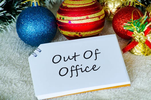Out Of Office text on white notepad with Christmas decoration. Holiday season concept.