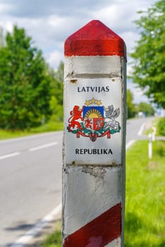red and white border stone between Latvia and Lithuania with the Latvian coat of arms on it
