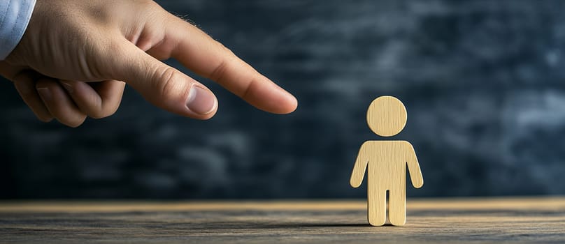 A hand reaches toward a wooden figure on a dark background, symbolizing choice or influence with copy space.