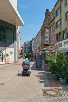 Pedestrian zone with stores and restaurants and a pensioner with an electric car on Sonnenwall in the city center of Duisburg