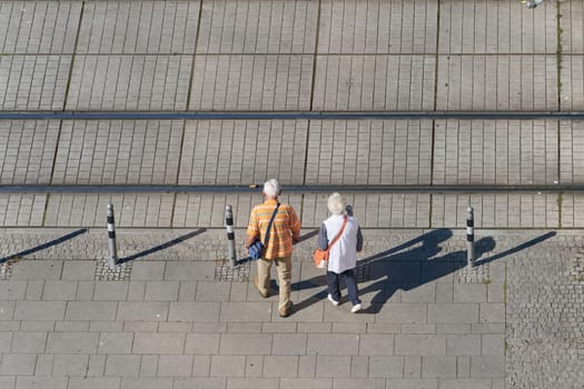 old pensioner couple crossing the tracks of a streetcar in the city center of Magdeburg in Germany
