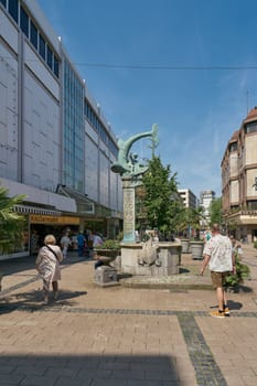Pedestrian zone with the Triton Brunnen, Triton fountain from 1902 and some passers-by in the city center of Duisburg in Germany