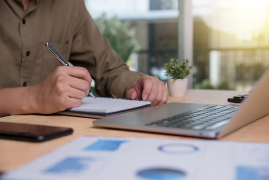 Businessperson writing notes while planning in an office setting, emphasizing strategic thinking and planning. Perfect for business articles