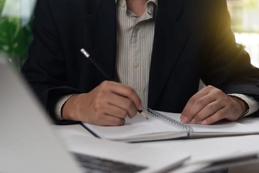 Businessperson writing notes in a notebook, emphasizing strategic thinking and planning. Ideal for business management content