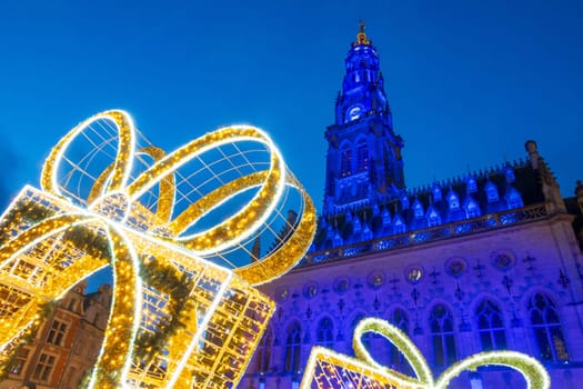 Arras, France - December 30, 2023: View of the Belfry and Christmas decorations on the illuminated square, photograph taken during the holiday season