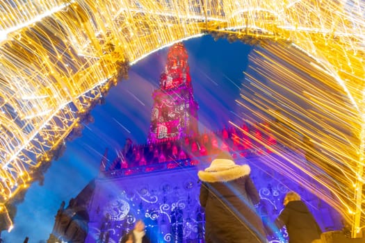 Arras, France - December 30, 2023: Creative view of Belfry and Christmas decorations on the illuminated square during the holiday season, intentional motion blur