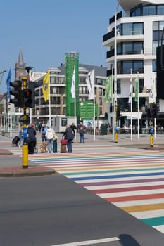 Crosswalk in rainbow colors with passers-by in the Belgian coastal town of Blankenberge in Flanders on the North Sea