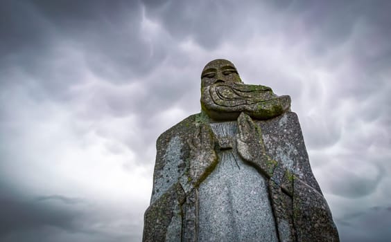 Carnoët, Bretagne, France - March 22, 2017: Detail of granite statue in the Valley of the Saints in a dramatic cloudy atmosphere