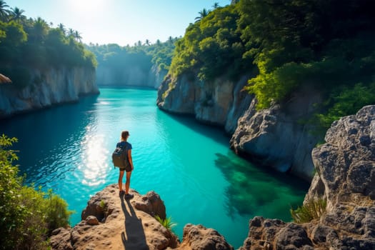 A lone traveler with a backpack stands on a cliff overlooking a pristine blue river surrounded by lush greenery in a tropical canyon. Ideal for travel, adventure, and nature themes