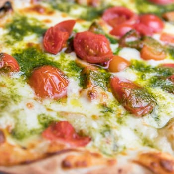 Closed pizza. Italian pizza with cherry tomatoes, pesto sauce basil and mozzarella cheese baked in a wood oven. Italian cuisine.