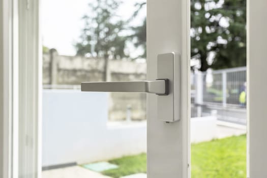 Aluminum window open detail. Metal door frame closeup view. Sound insulation. Energy efficient, safety profile, blur garden outdoor background.