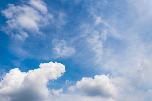 Fluffy white clouds on clear blue sky background