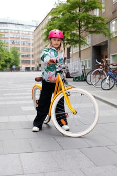 young girl with yellow bicycle in the city