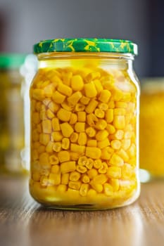 Canned sweet corn in jar on a wooden table.