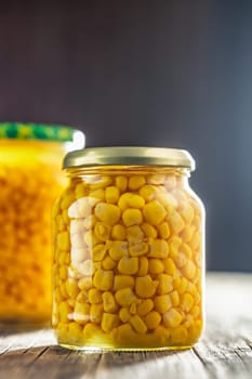 Canned sweet corn in jar on a wooden table.