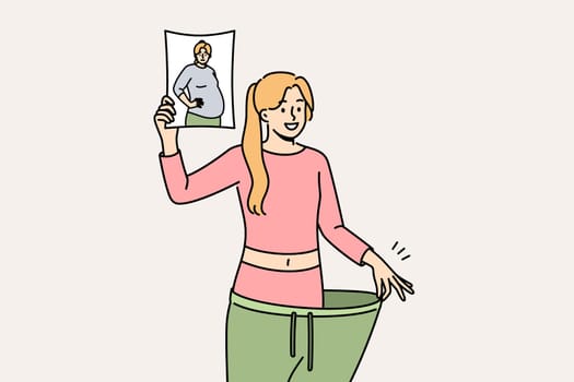 Lost weight woman in huge pants, showing own old photo with big belly and fat or cellulite on hips. Lost weight girl is proud of transformation achieved thanks to low-carb diet and regular fitness