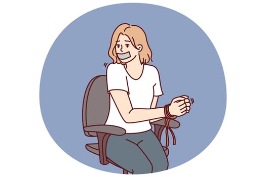 Woman hostage with bound hands sits in chair after being kidnapped or attacked by criminals. Girl with sealed mouth became hostage during attack by robbers on company office or bank branch