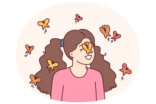 Little girl among butterflies flying and landing on face for spring mood concept. Happy childhood of preteen girl loving animals and laughing at sight of butterflies in summer park
