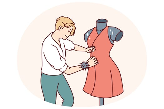 Man fashion designer sews dress fixed on mannequin preparing women outfit for Paris haute couture week. Professional fashion designer makes exclusive elegant clothes for girls to order