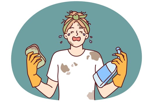 Woman housewife in dirty clothes is crying because of large amount housework and lack of rest. Girl housewife with tears in eyes holds sponge and spray bottle for cleaning in apartment
