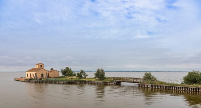 Comacchio, Italy - 13 June 2024. Casone Donnabona, traditional house for fishermen in lagoon. Wetland, blue sky.