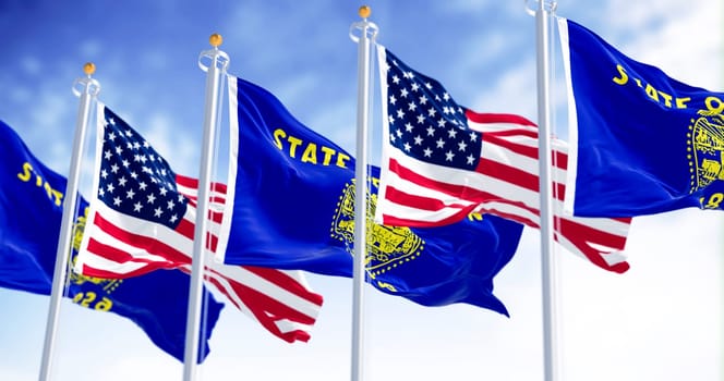 Oregon state flags waving in the wind with the american flags on a clear day. The Oregon flag is two-sided with navy blue and gold colors. Selective focus. Fluttering fabric. Waving flag