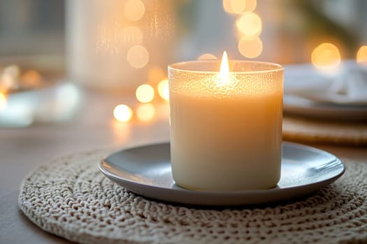 A lit candle on a slate plate adds a cozy touch to the table, surrounded by softly glowing lights in a serene setting.