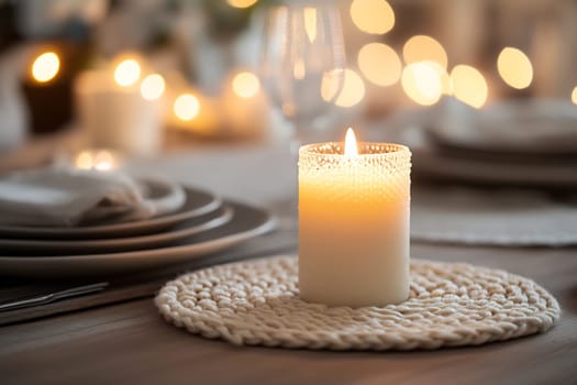 A beautifully arranged dining table features a glowing candle, plates, and soft lights creating a warm ambiance for a special occasion.