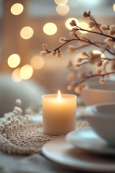 A soft candle glows warmly beside delicate flowers, creating a cozy atmosphere for a dinner setting with elegant tableware.