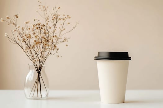 A minimalist arrangement features a white coffee cup beside a vase of dried flowers, creating a serene atmosphere in a calm setting.