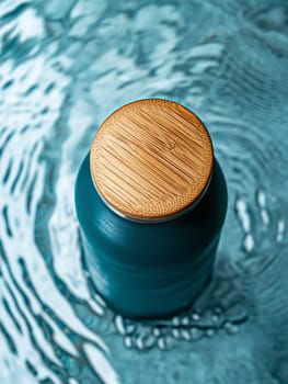 A water bottle with a bamboo lid rests on a textured blue surface, highlighting its sleek design and modern aesthetic.