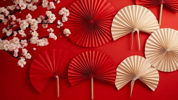 Red and cream paper fans are artistically arranged on a vibrant red wall, complemented by delicate cherry blossoms.