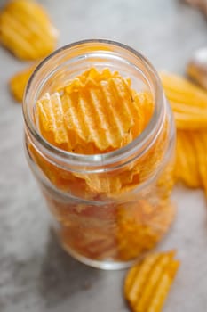 Crispy potato chips in jar on a kitchen table.