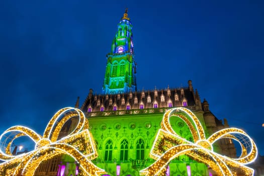 Arras, France - December 30, 2023: View of the Belfry and Christmas decorations on the illuminated square, photograph taken during the holiday season