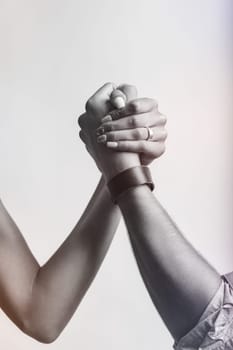The clasped hands represent a subtle but powerful 'battle of the sexes.' What appears friendly holds an underlying struggle for balance and strength in this symbolic competition