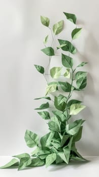 A green leafy plant made of paper. The leaves are folded and the stem is thin. The plant is placed on a white surface