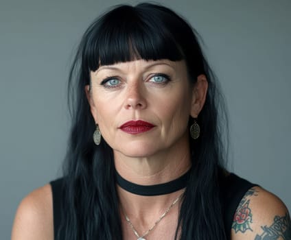 Close-up portrait of a middle-aged woman with black hair, blue eyes and dark red lipstick earrings and necklace. She has tattoos on her arms. AI generative.