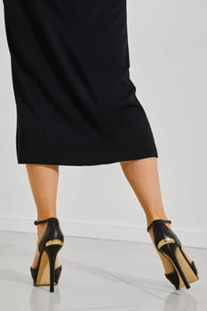 Rear view of a stylish high heels worn by a woman dressed in a black outfit