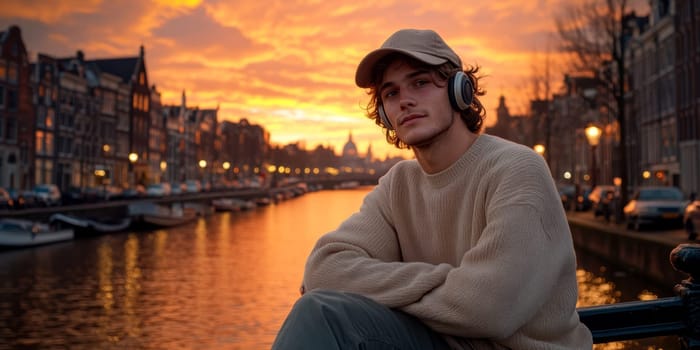 A young man leaning against a wall near the canals, wearing an oversized sweater and a baseball cap, listening to music through his vintage headphones. AI generative.
