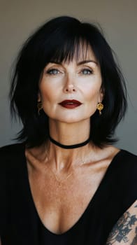 Close-up portrait of a middle-aged woman with black hair, blue eyes and dark red lipstick earrings and necklace. She has tattoos on her arms. AI generative.