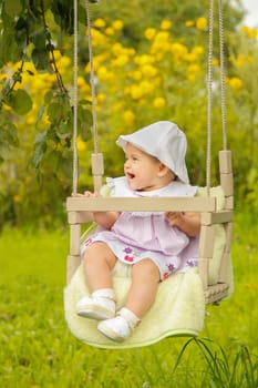 A joyful and happy baby is having a great time enjoying a swing in a vibrant and colorful garden area