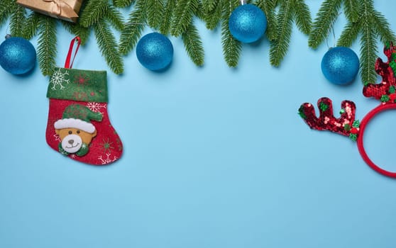 Spruce branches and Christmas toys on a blue background, top view