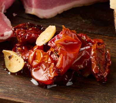 Sun dried tomatoes with garlic pieces on a wooden board