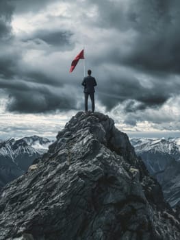 A businessman, victorious, stands with a red flag on a mountain summit, encapsulating success and leadership in a striking natural setting