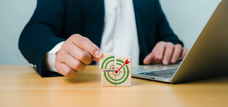 Male hand putting stack of wooden blocks with target icon on wooden table white background copy space, Business goals and objective concepts, Business competition.