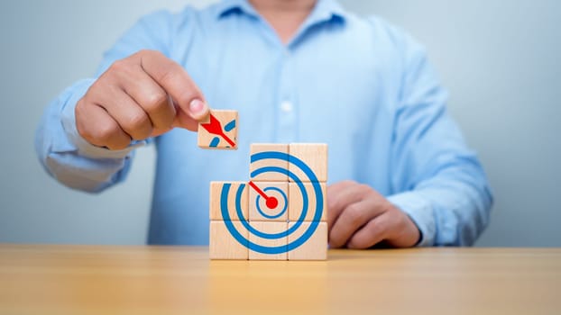 Businessman hands are completing wooden blocks with target sign. Startup concept. Business concept. Management concept. Business planning concept.